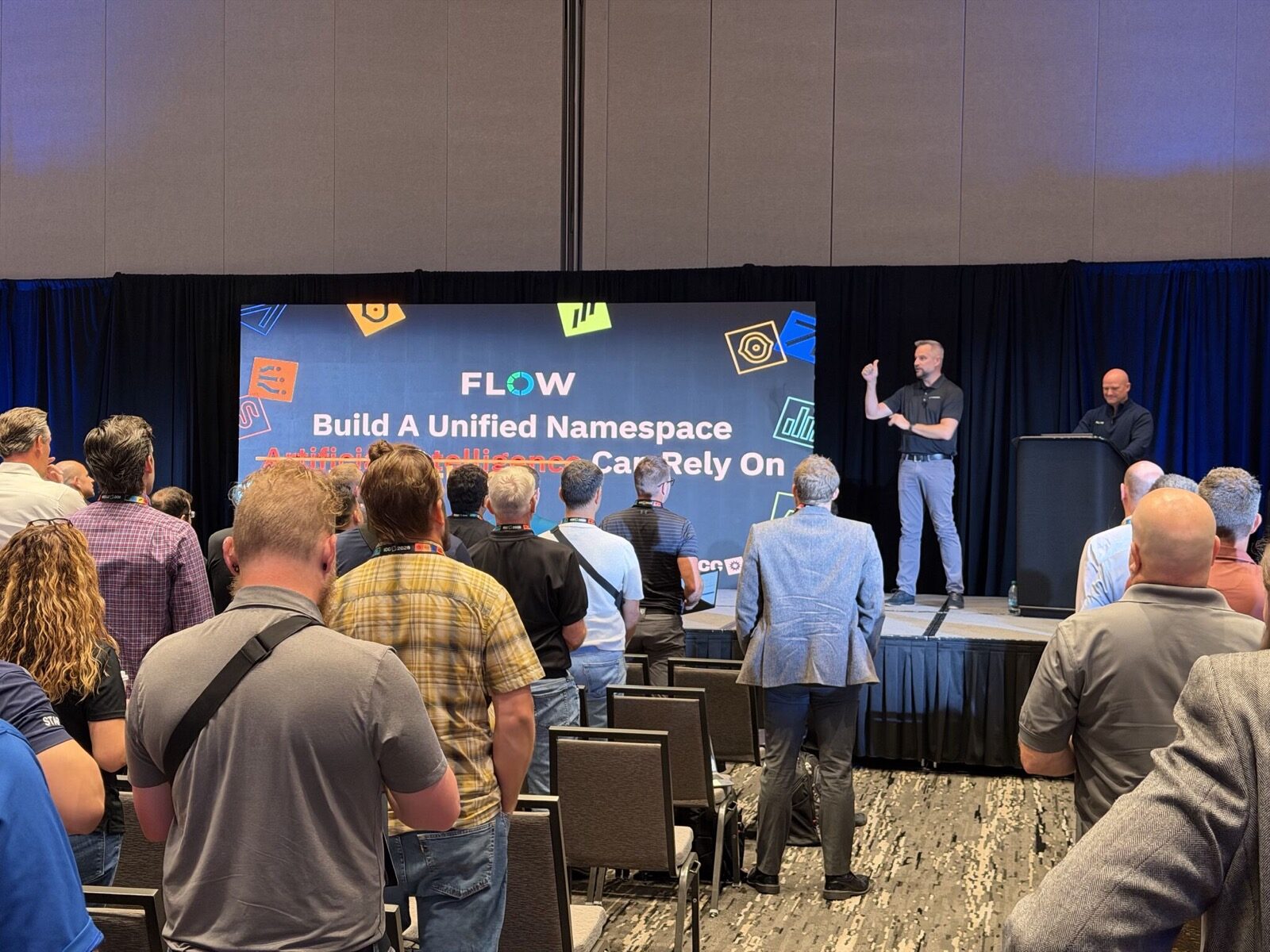 Jeff presenting on stage in front of a Flow slide reading Build A Unified Namespace, with Artificial Intelligence struck through, Can Rely On
